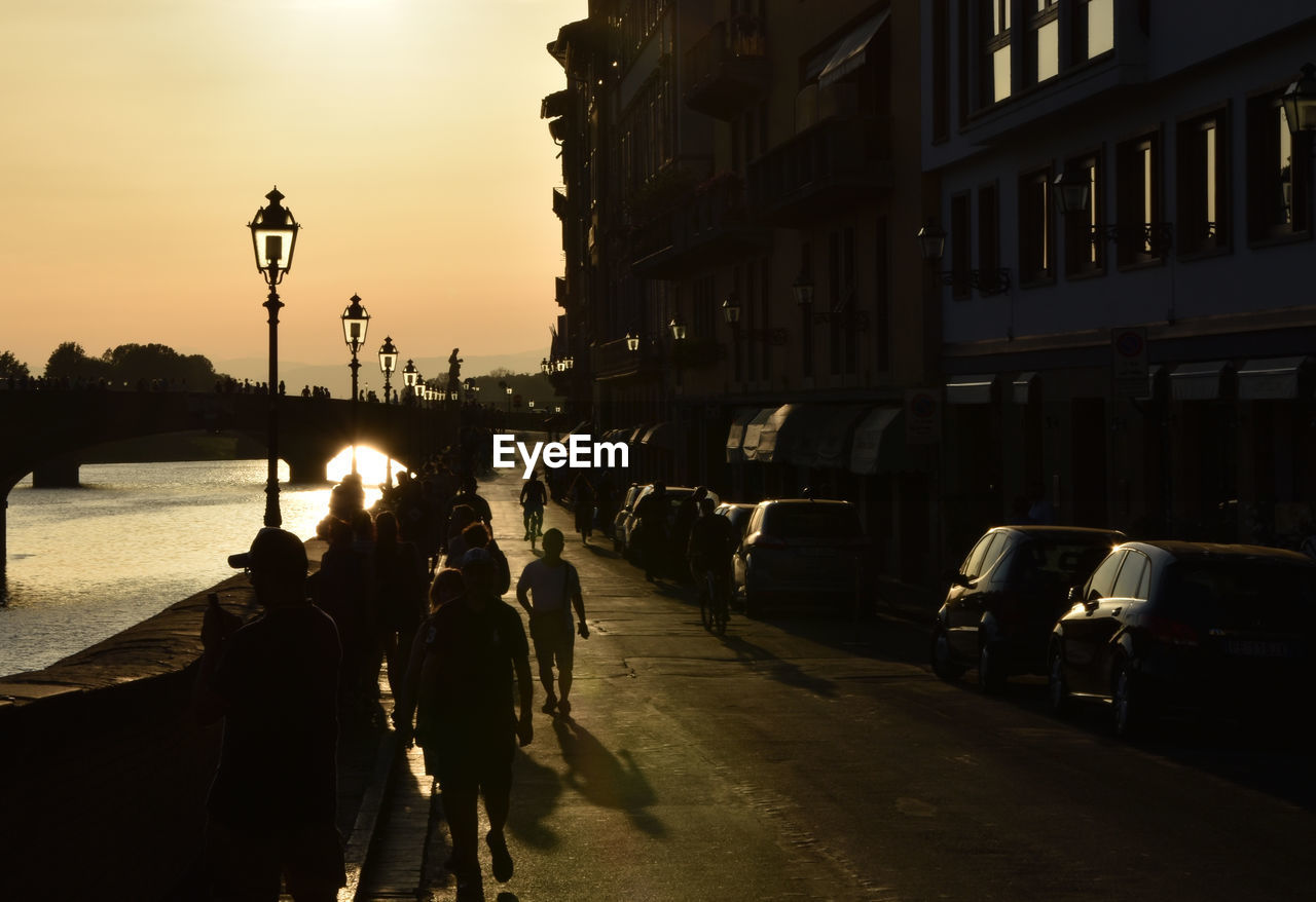 PEOPLE ON ILLUMINATED STREET AT SUNSET