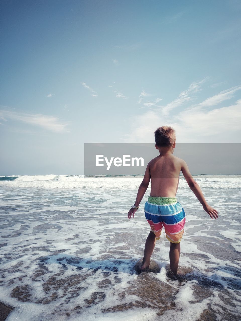 rear view of shirtless man standing at beach