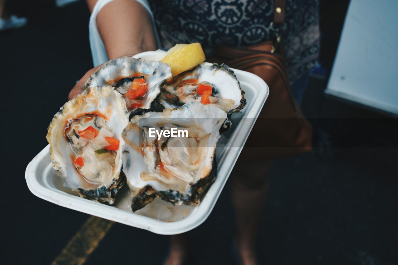 Low section of woman holding oysters in plate