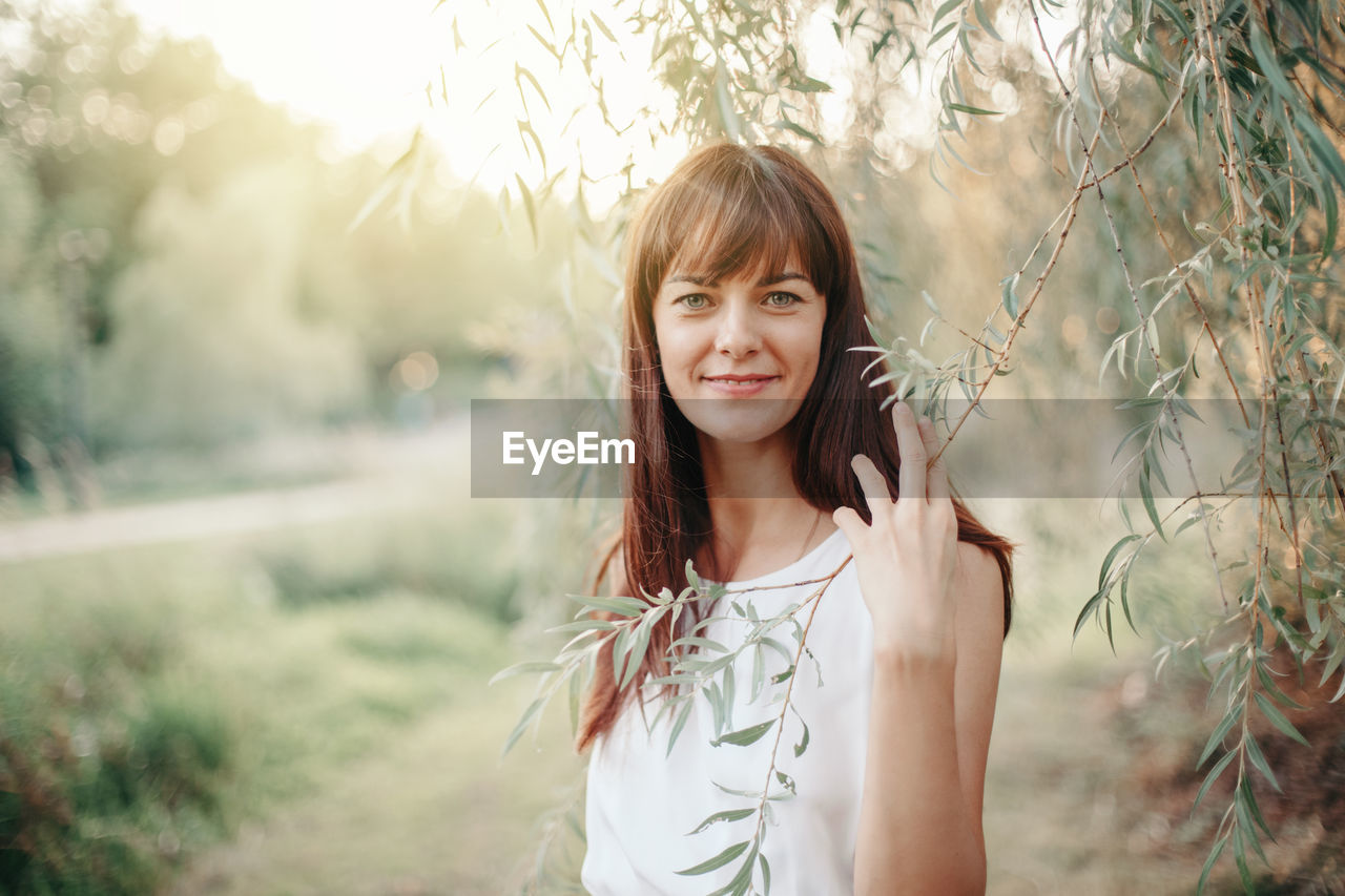 Portrait of smiling woman by tree