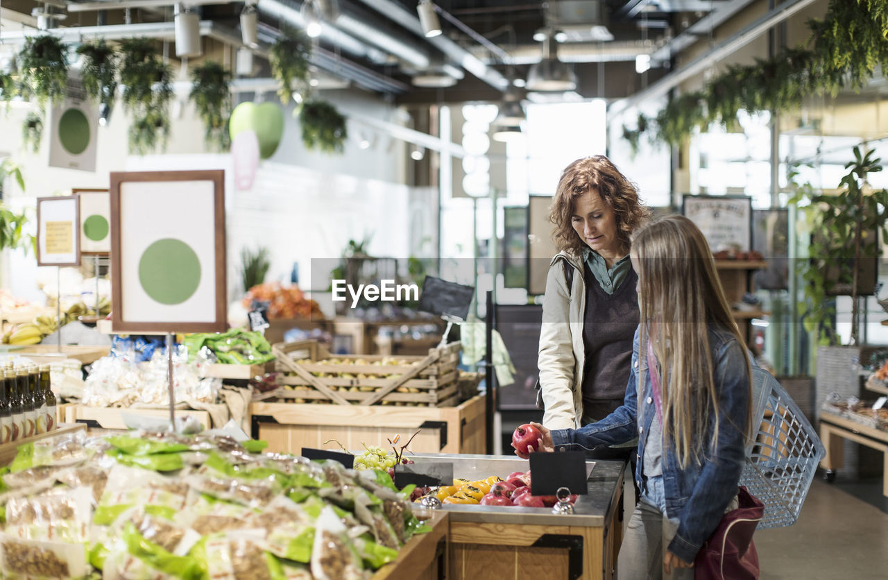 Mother and daughter buying fresh pomegranates in organic store