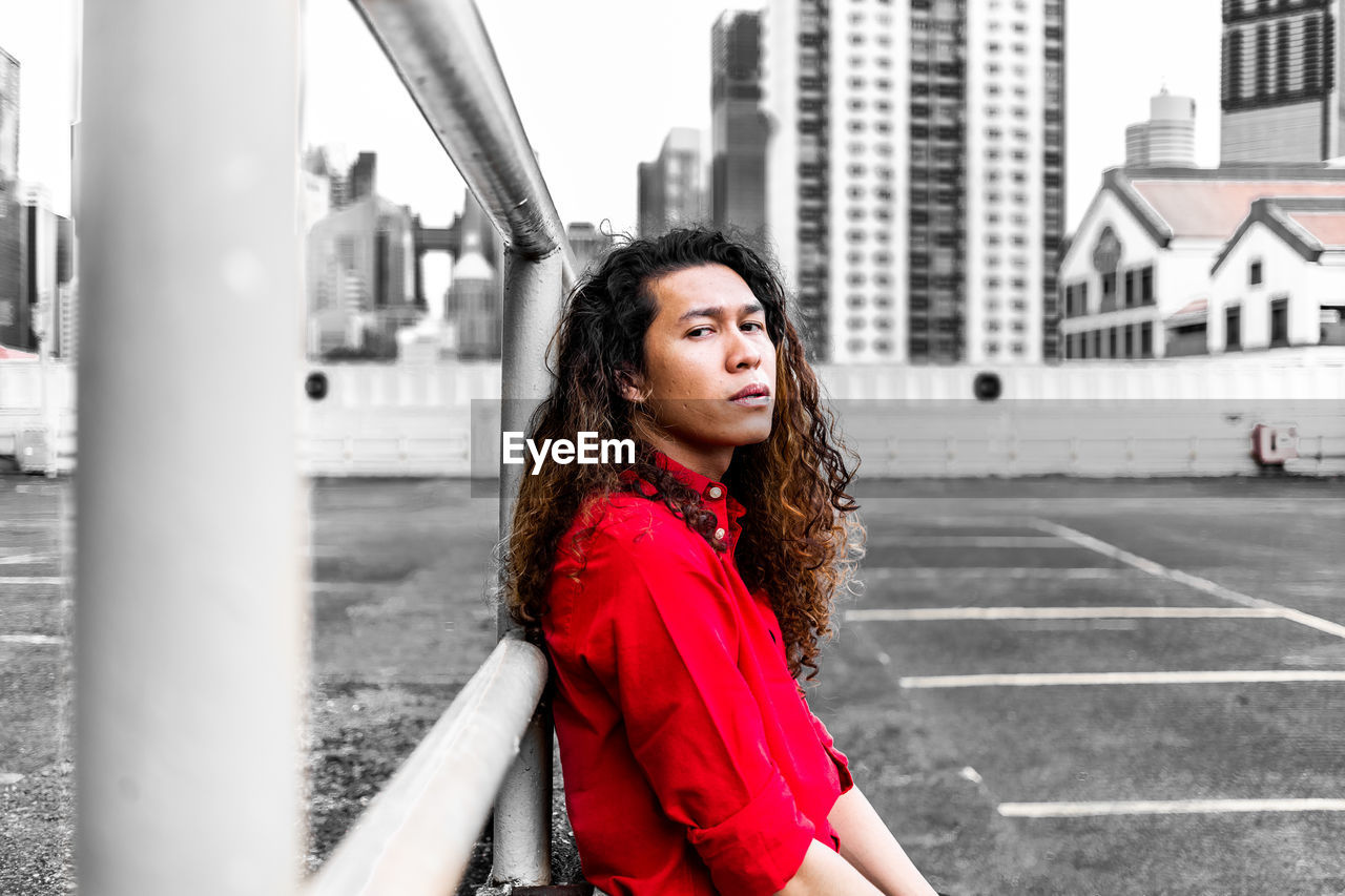 PORTRAIT OF BEAUTIFUL YOUNG WOMAN STANDING BY RAILING IN CITY