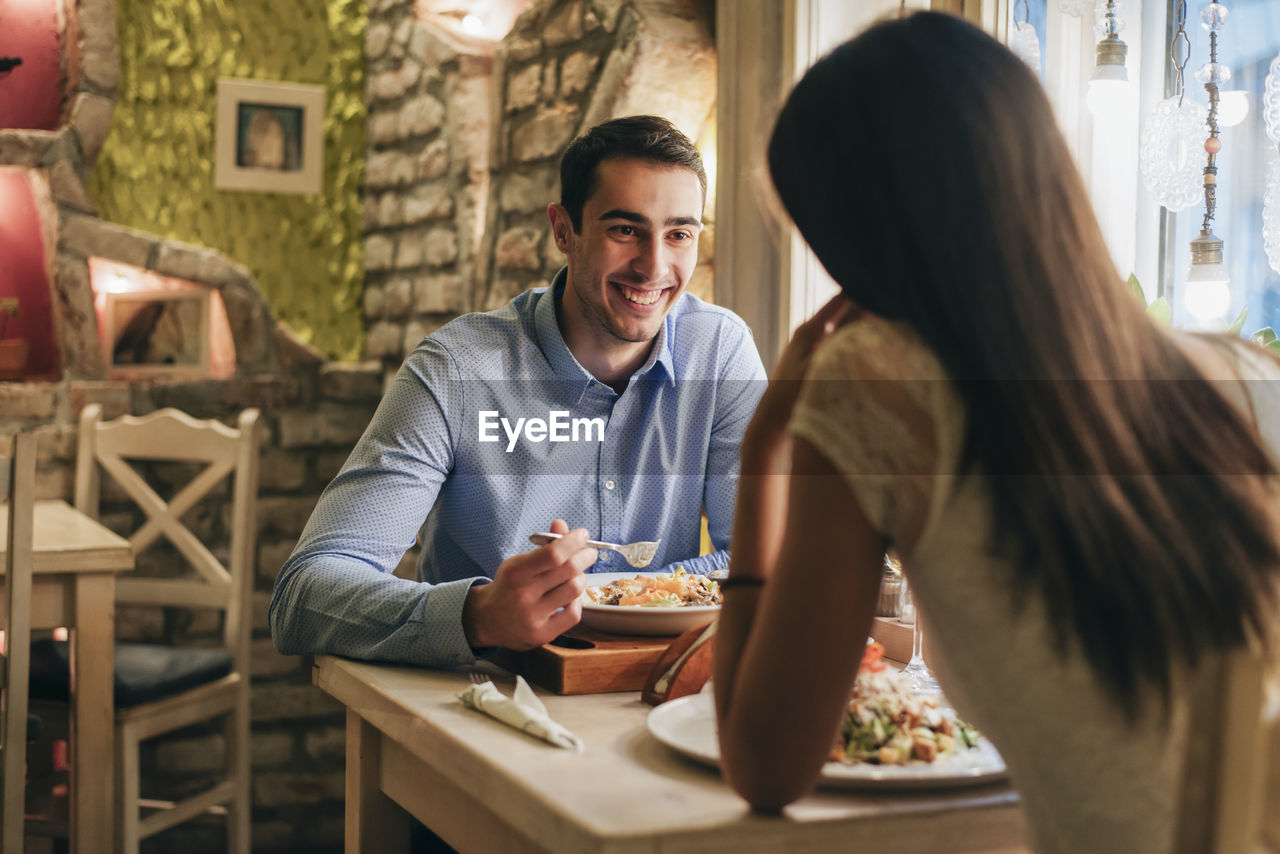 Portrait of happy young man having dinner with his girlfriend in a restaurant