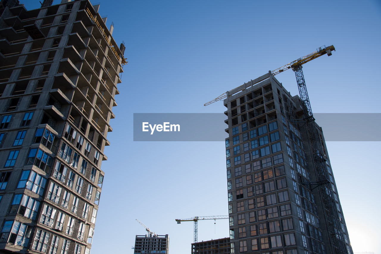 Tower crane working at construction site on blue sky background with white clouds. construction 