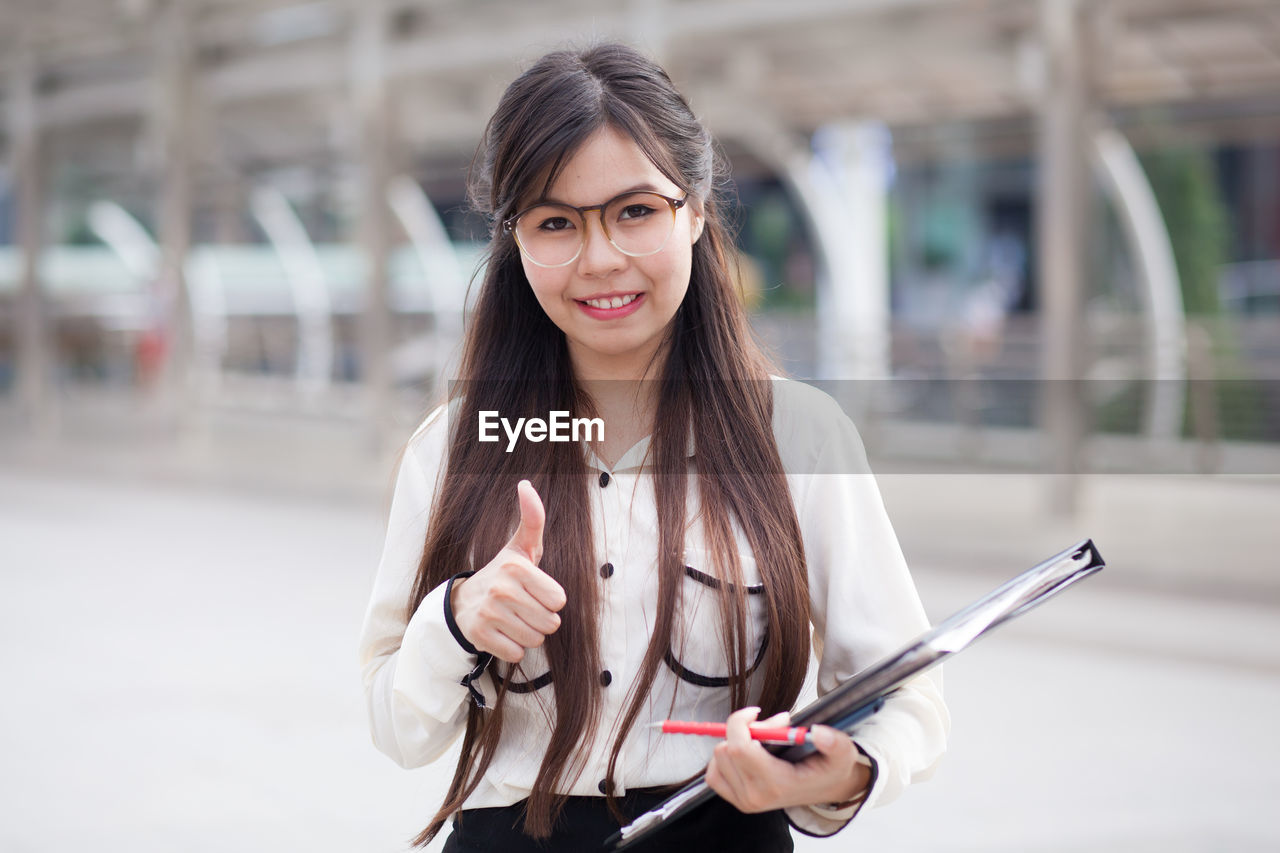 Portrait of young businesswoman gesturing while standing outdoors