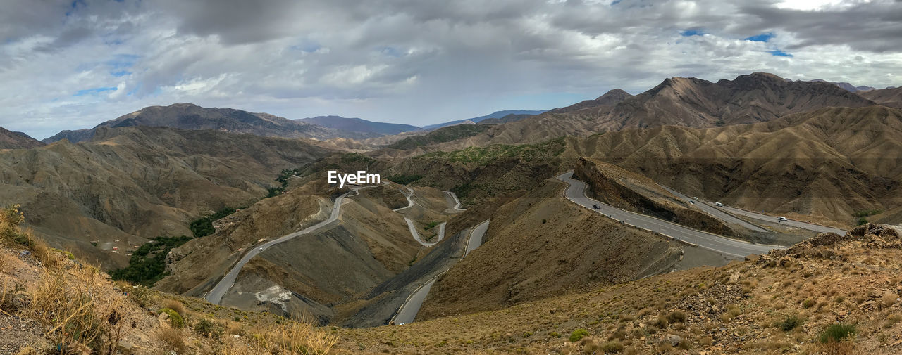 Amazing rocky atlas desert roads - panoramic view of landscape against cloudy sky