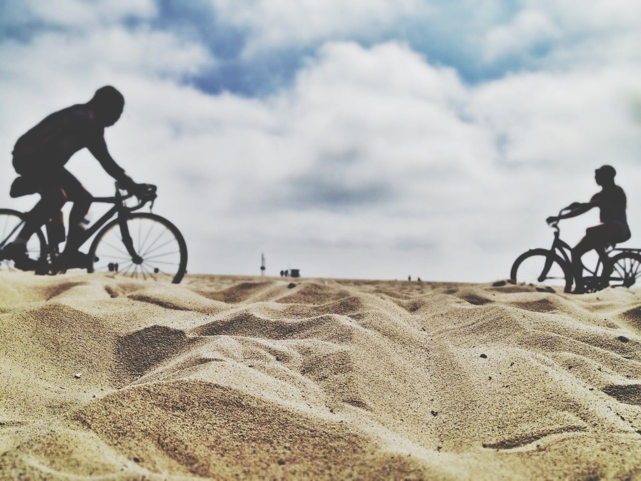 Side view of people bicycling on beach