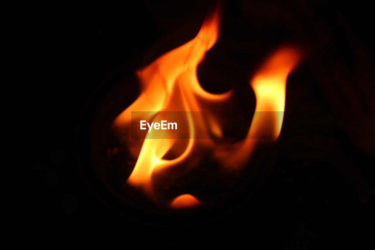 CLOSE-UP OF LIT CANDLE IN DARK