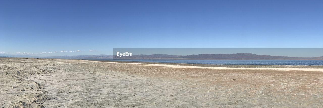 Scenic view of beach against clear blue sky