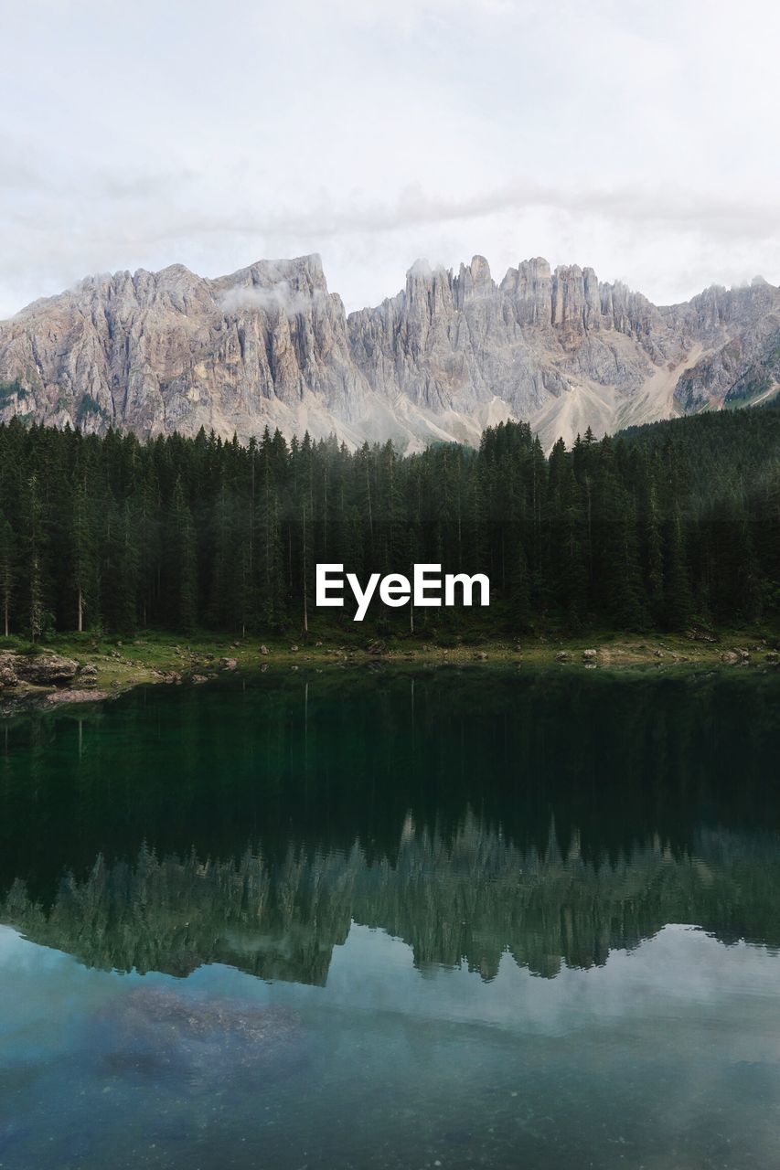 Scenic view of trees and rocky mountains reflection in lake against sky