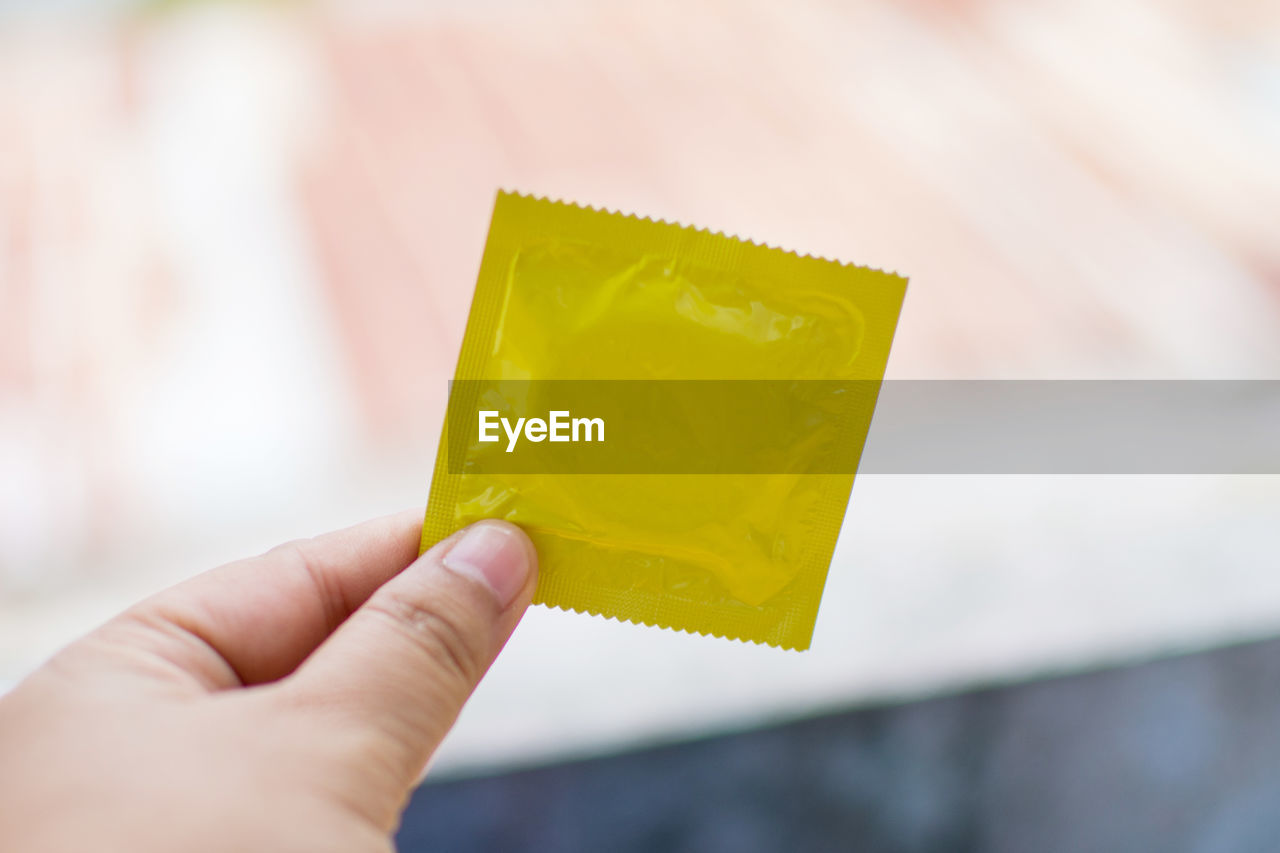 Close-up of man holding condom outdoors