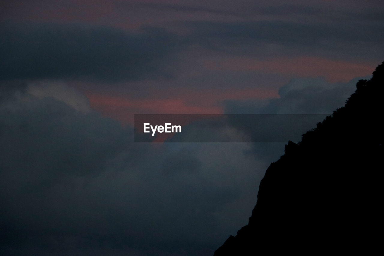 LOW ANGLE VIEW OF SILHOUETTE MOUNTAIN AGAINST DRAMATIC SKY