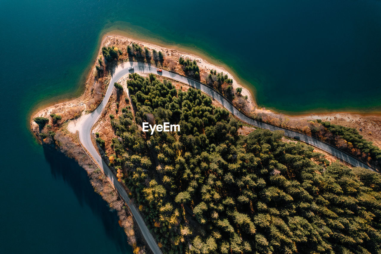 Aerial view of road by forest and lake in autumn