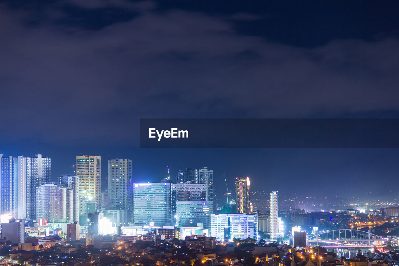 Illuminated buildings in city against sky at night