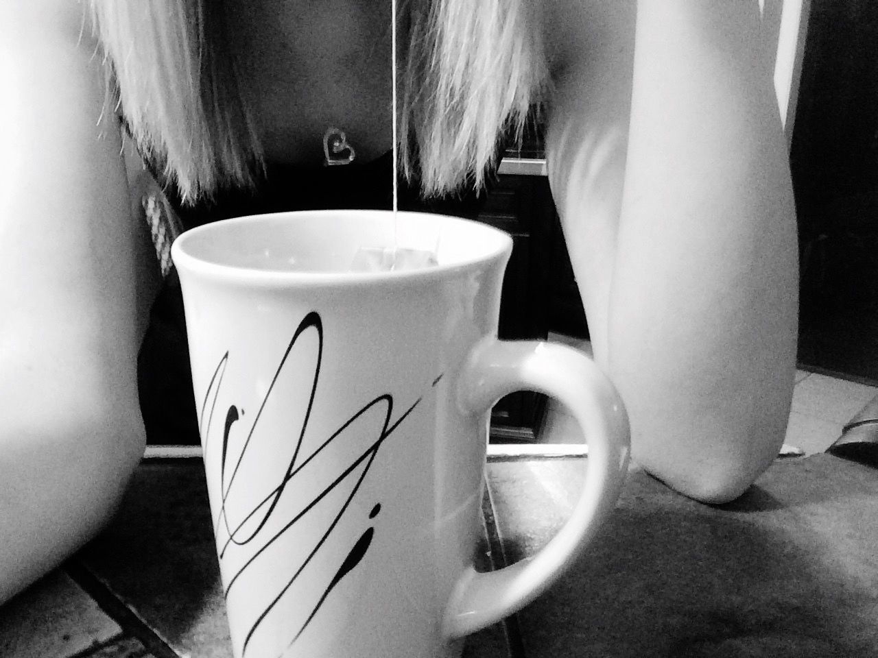 Close-up mid section of women with coffee mug on table