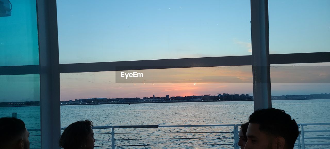 REFLECTION OF PEOPLE ON WINDOW DURING SUNSET