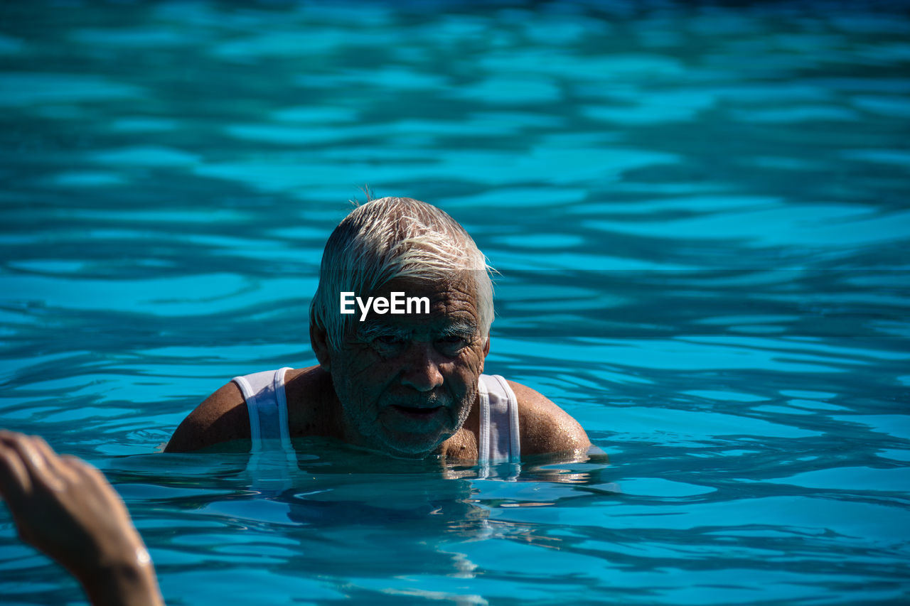 CLOSE-UP PORTRAIT OF MAN SWIMMING IN POOL