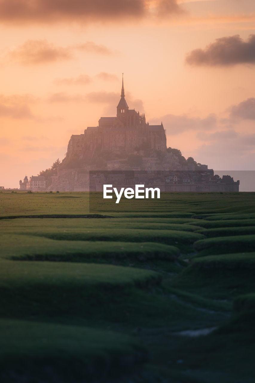 Scenic view of mont saint michel against sky during sunset