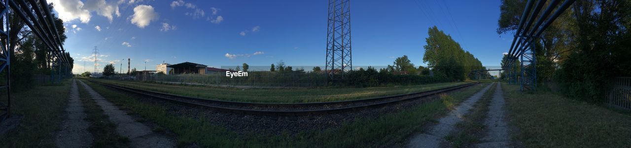 PANORAMIC SHOT OF RAILROAD TRACKS BY BUILDINGS AGAINST SKY