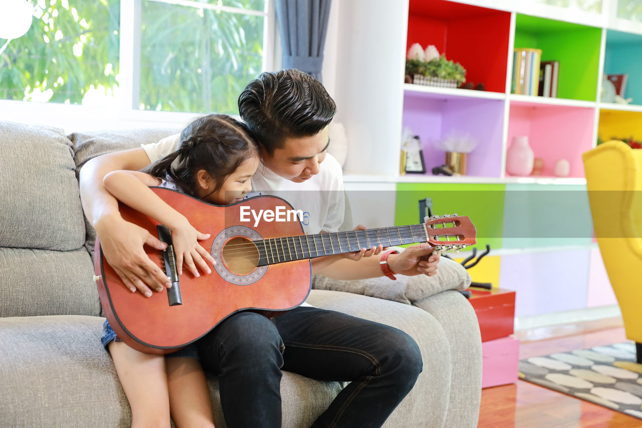 COUPLE PLAYING GUITAR AT HOME