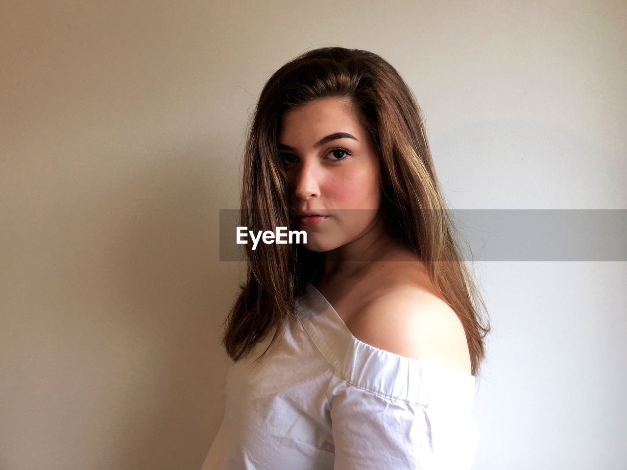 Portrait of beautiful young woman standing against wall