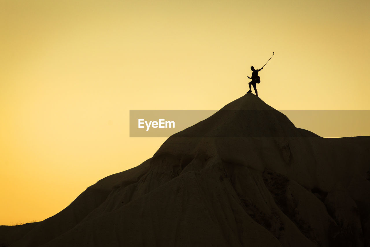 LOW ANGLE VIEW OF SILHOUETTE CROSS AGAINST MOUNTAIN DURING SUNSET