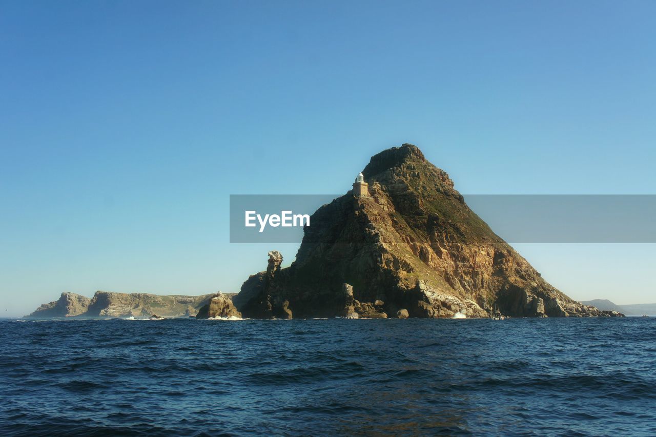 Rock mountain at sea against sky