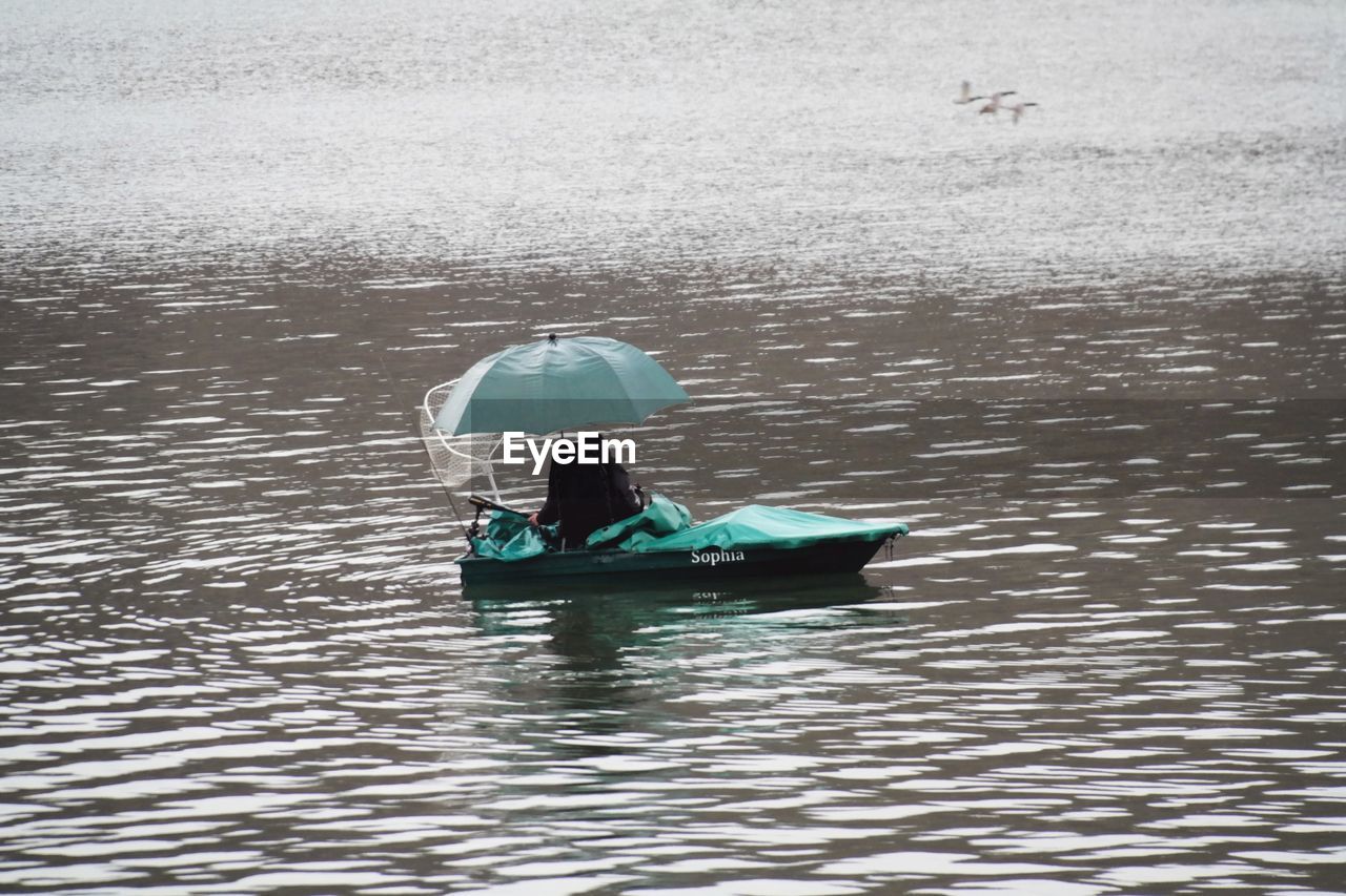REAR VIEW OF MAN IN BOAT AT LAKE