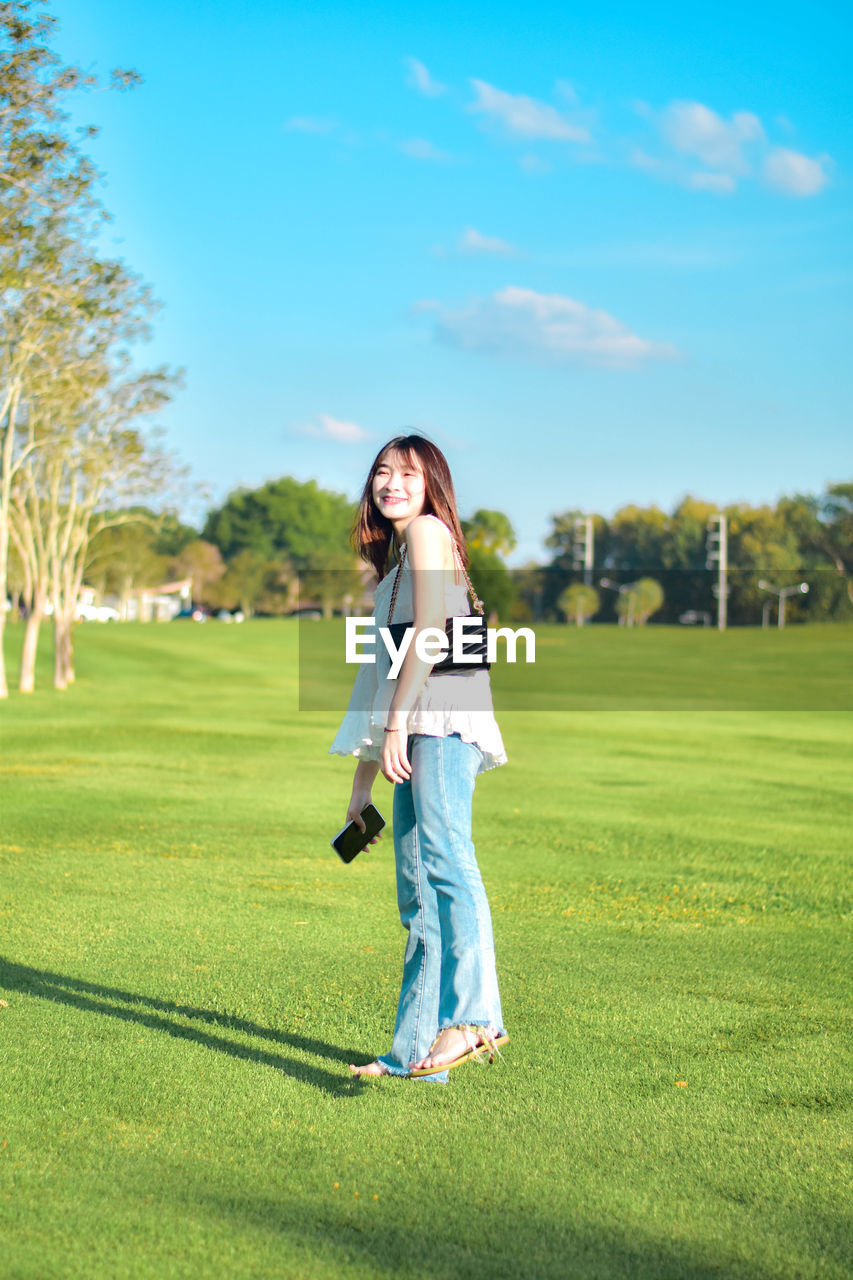 grass, full length, leisure activity, plant, adult, women, casual clothing, one person, activity, nature, sports, happiness, green, golf, emotion, golf course, young adult, smiling, sky, standing, tree, lifestyles, sunlight, lawn, cheerful, female, weekend activities, portrait, day, enjoyment, shadow, brown hair, long hair, relaxation, recreation, copy space, positive emotion, hairstyle, outdoors, fashion, looking, golf club, summer, green - golf course, holding, fun, person, front view