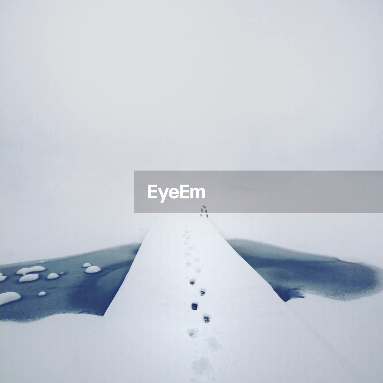 Snow covered pier on frozen lake against sky