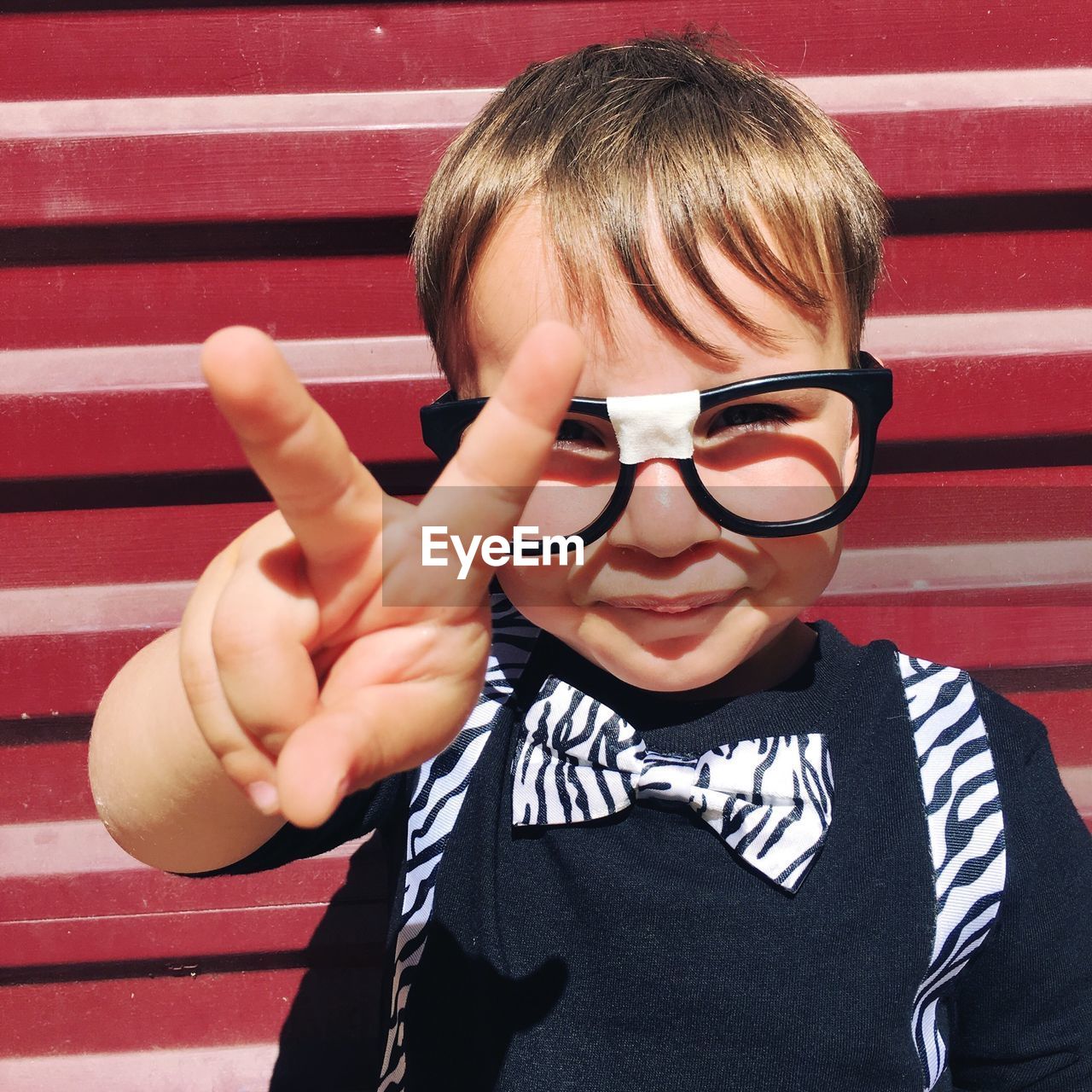 Close-up portrait of cute boy showing peace sign