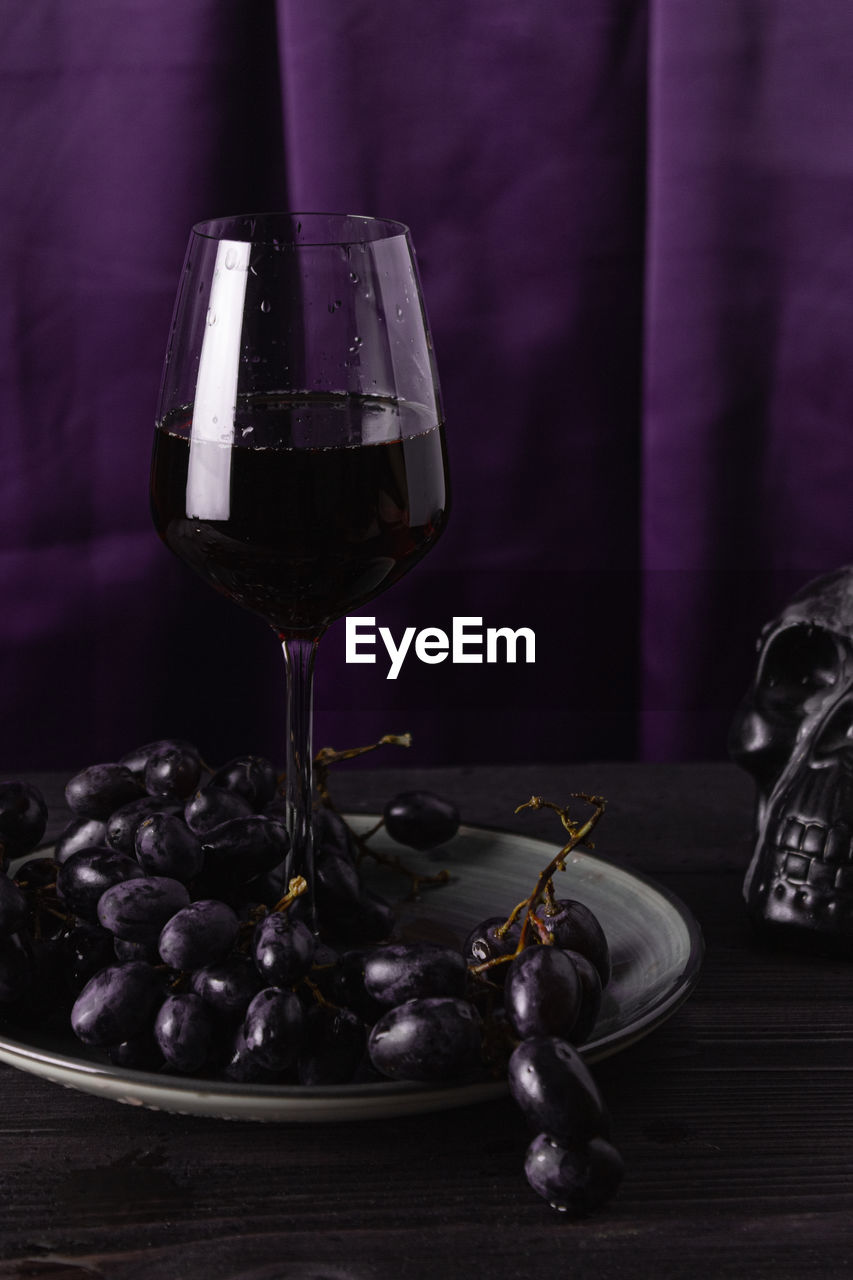 CLOSE-UP OF WINE GLASS WITH BOTTLES ON TABLE