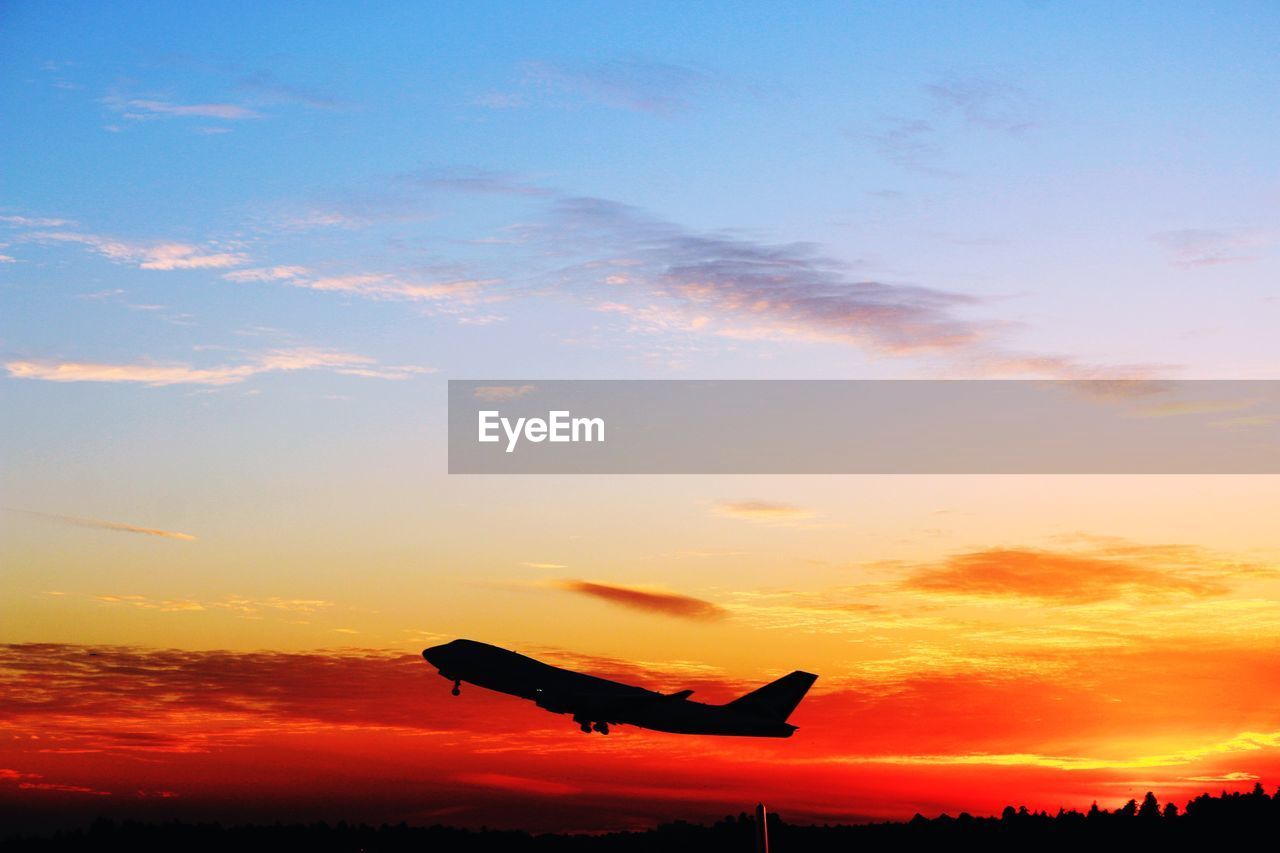 SILHOUETTE AIRPLANE FLYING AGAINST ORANGE SKY