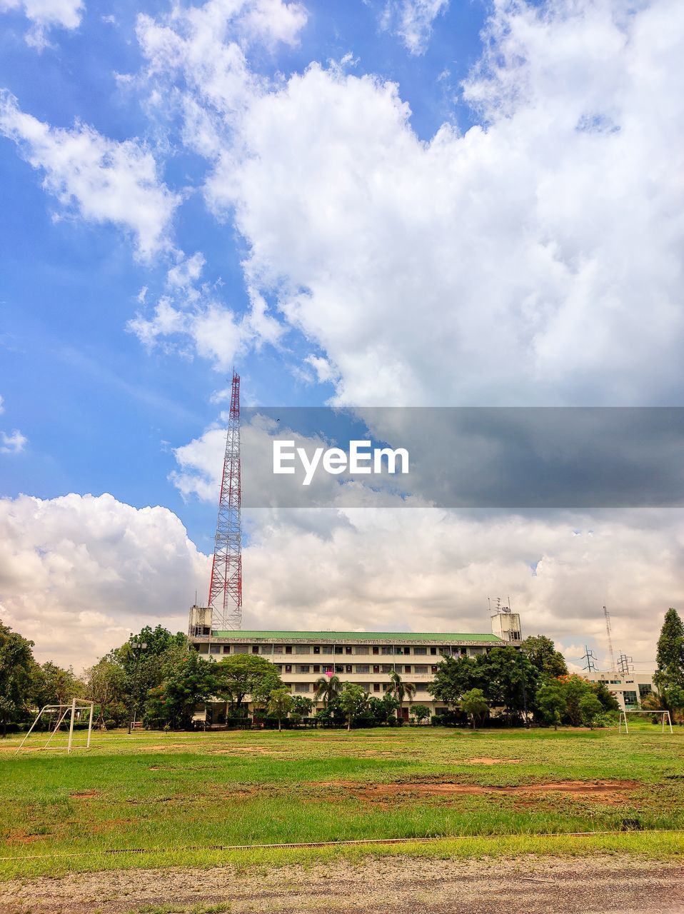 The telecommunication tower behide the building on field against sky