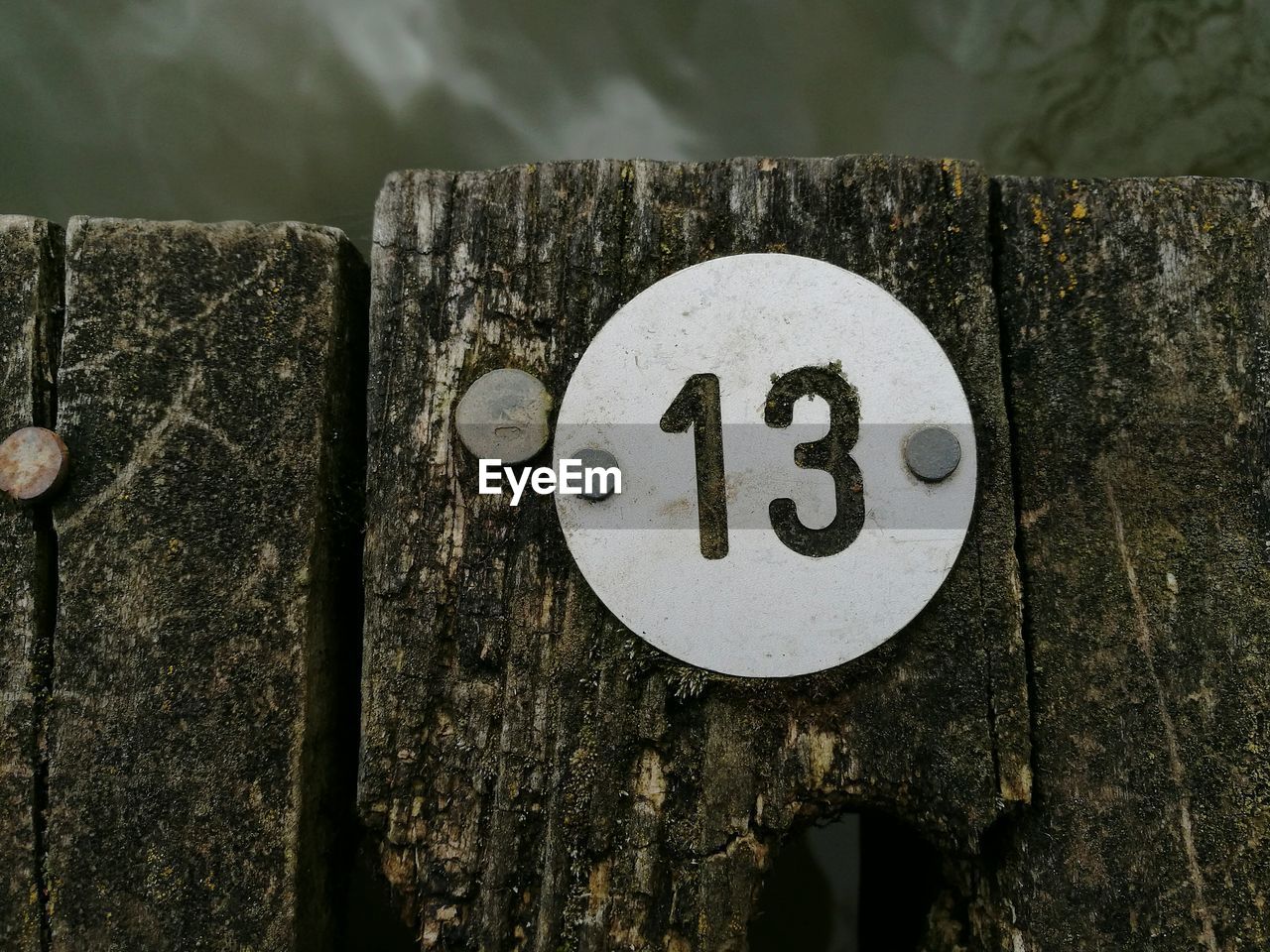 Close-up of number 13 on wooden pier in lake