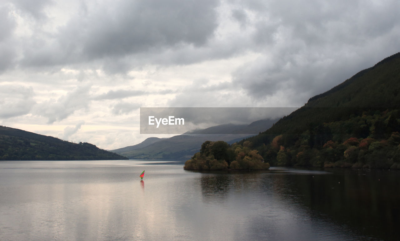 Scenic view of river and mountains against cloudy sky