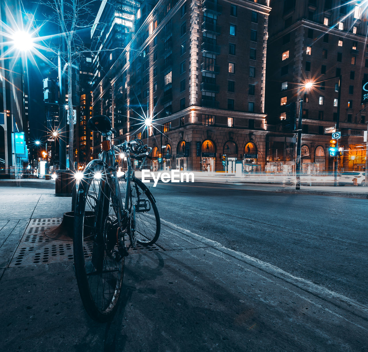 BICYCLES ON STREET BY BUILDINGS AT NIGHT