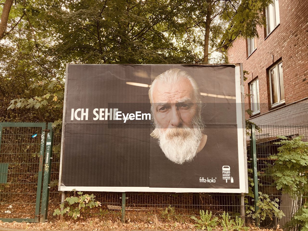 PORTRAIT OF MAN WITH TEXT ON PLANT AGAINST TREES