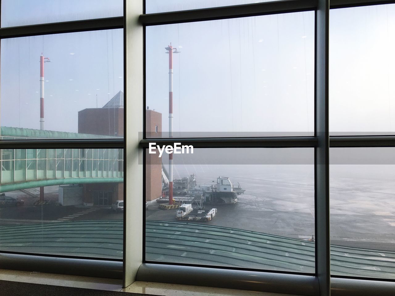 Airport runway seen through window during foggy weather