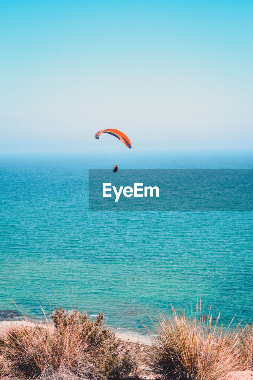 Scenic view of sea against sky with paraglider 