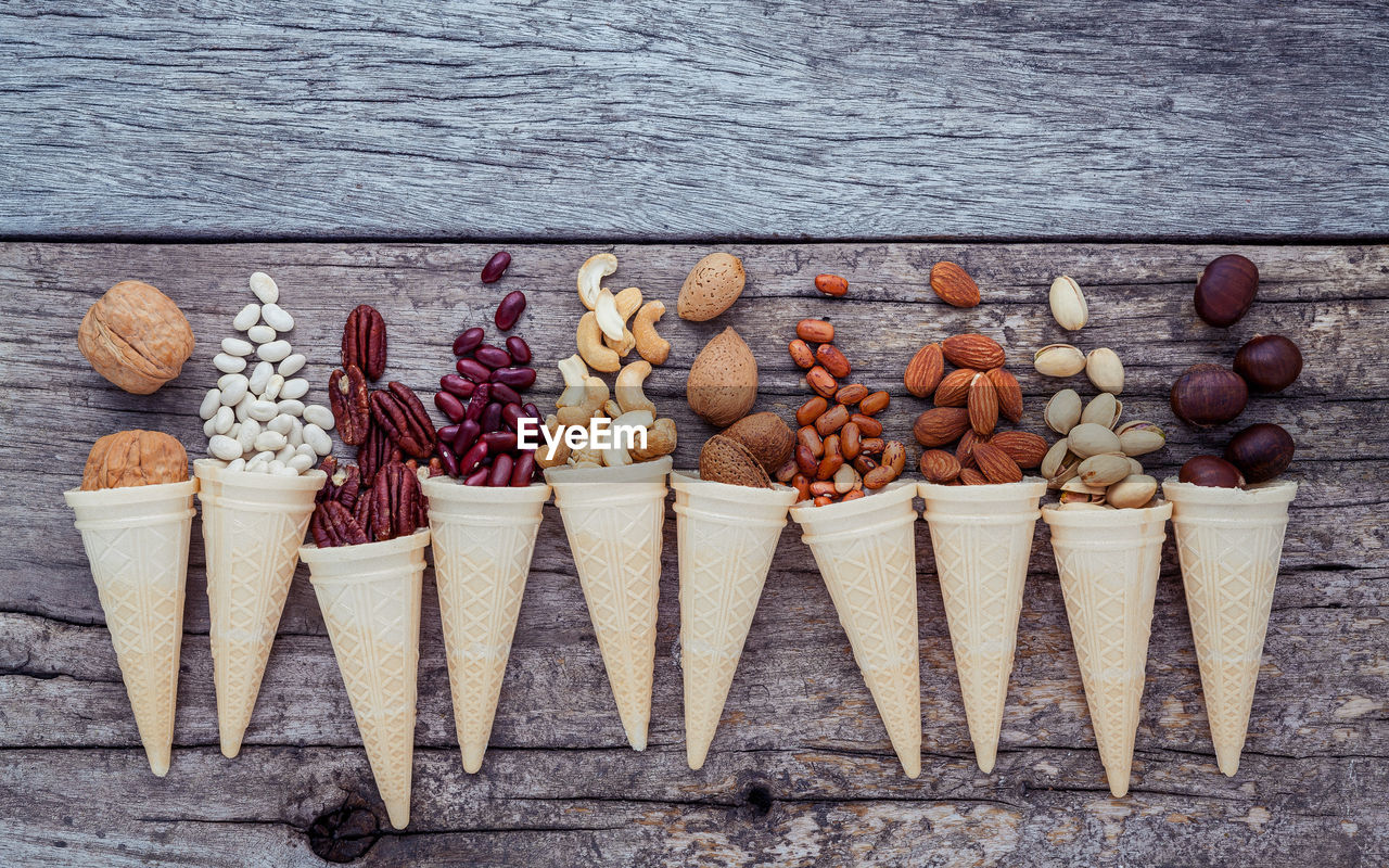 Directly above view of nuts and beans with ice cream cones on wooden table