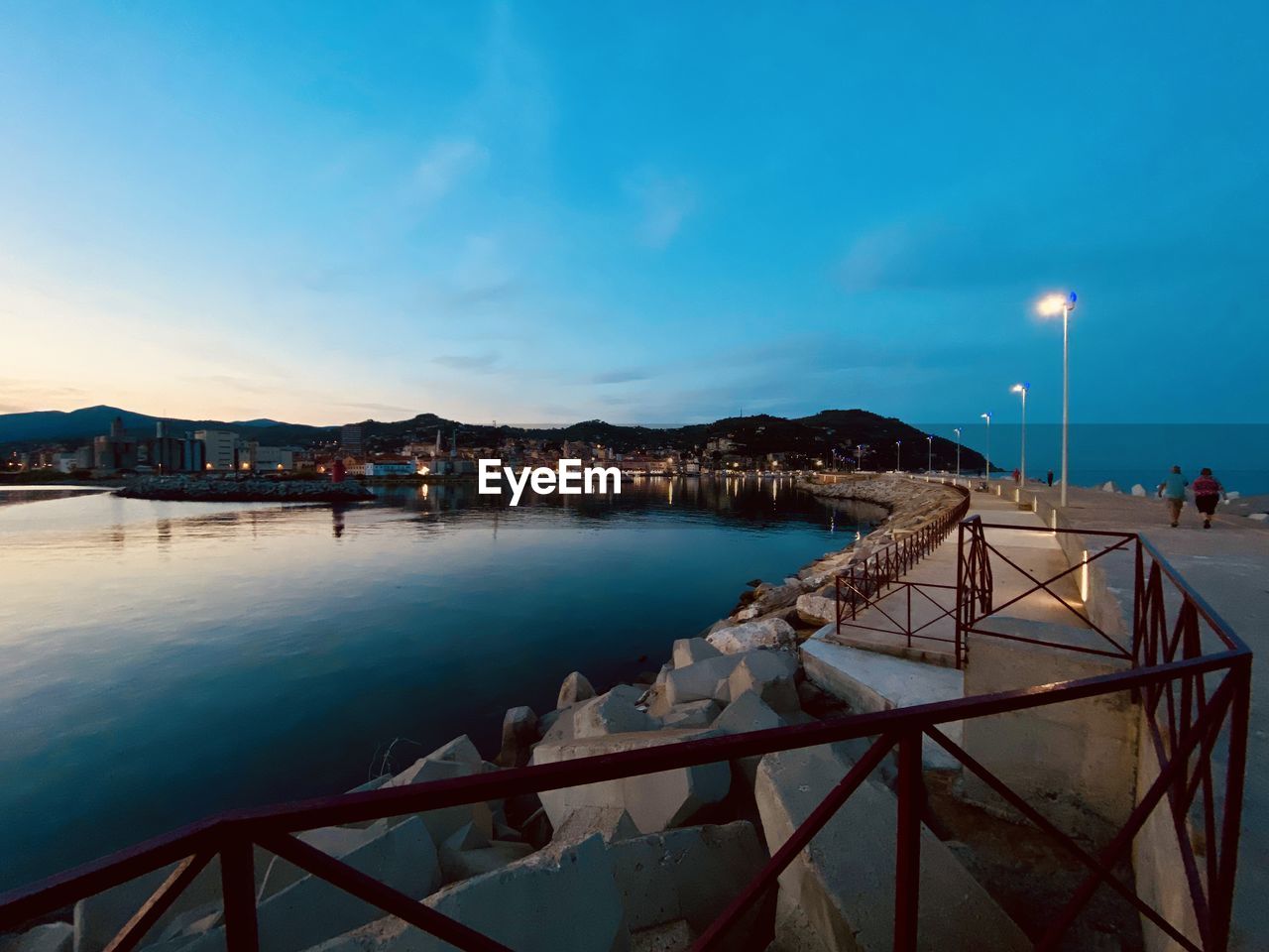 ILLUMINATED CITY BY SEA AGAINST BLUE SKY