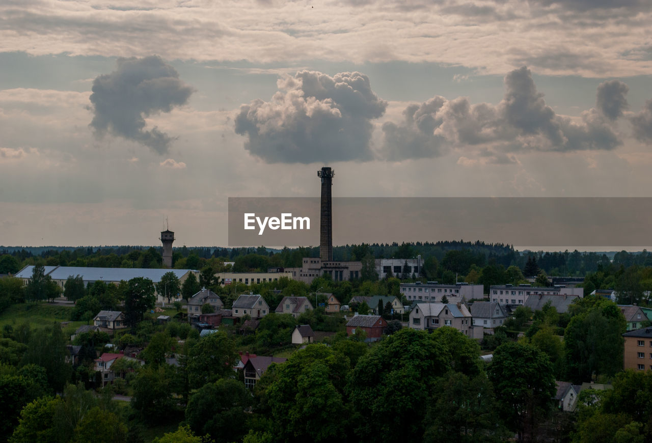 Smoke stack and houses in town against sky