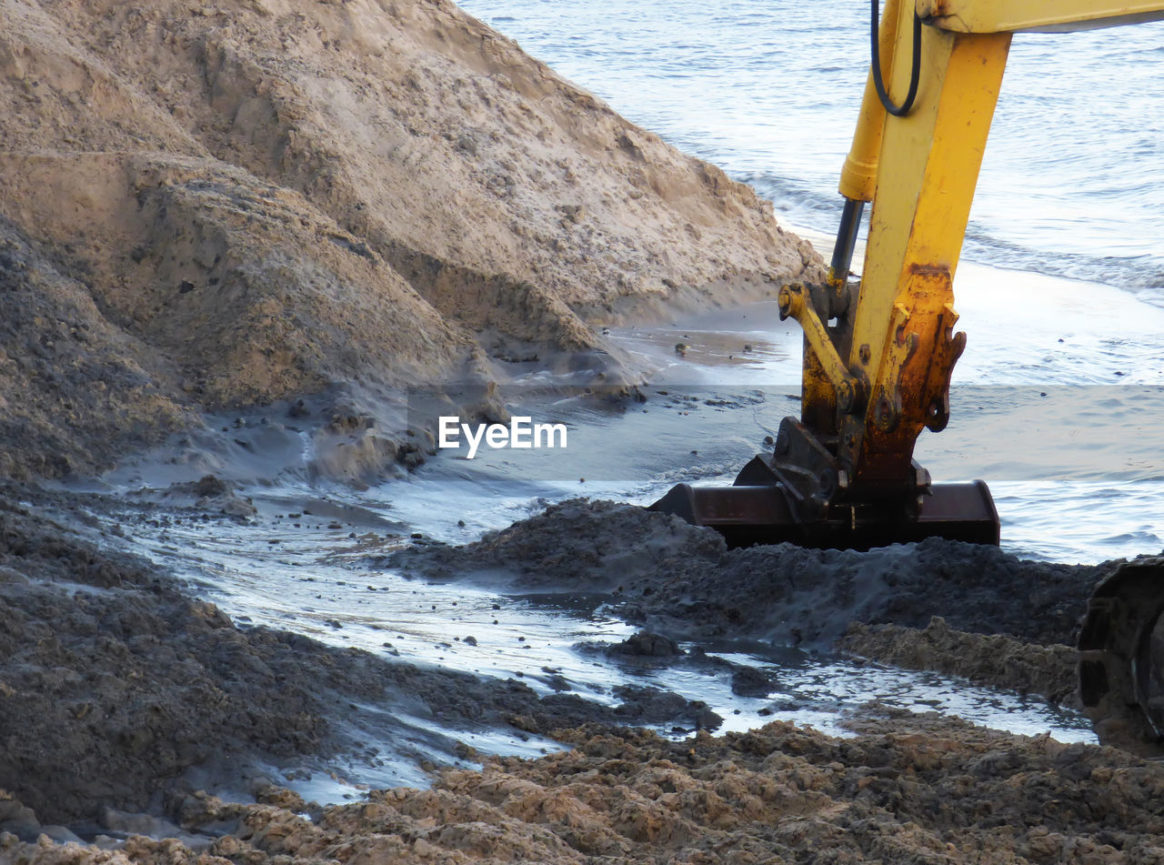 Cropped image of earth mover at beach