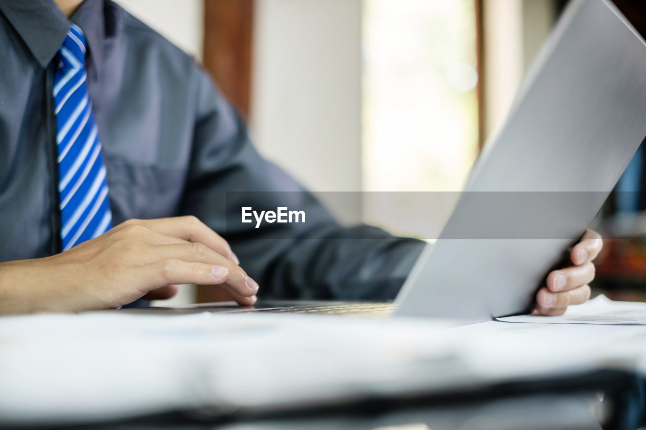 midsection of businessman using laptop at office