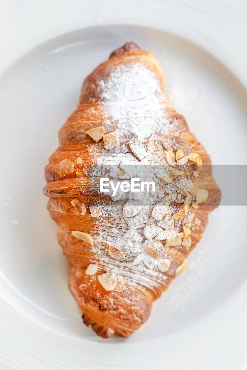 Top view of a delicious fresh almond croissant on a plate, perfect addition to the morning coffee