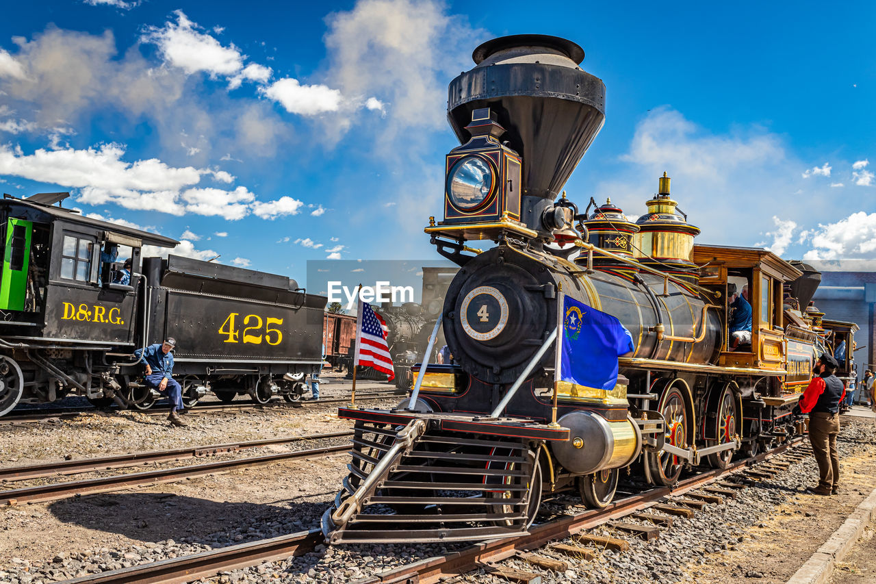 locomotive, rail transportation, train, track, transportation, transport, railroad track, railway, sky, mode of transportation, vehicle, cloud, land vehicle, nature, public transportation, steam train, rolling stock, steam engine, travel, day, sunlight, outdoors, railroad car, no people, architecture, blue, railroad station