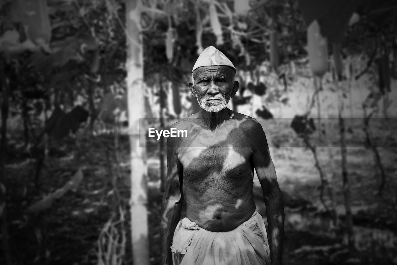 Portrait of senior man standing against trees