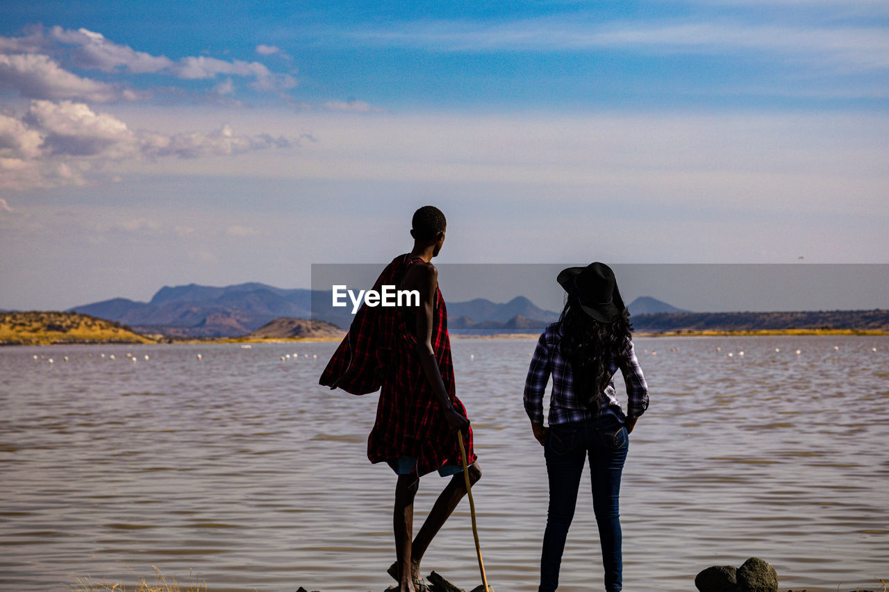 water, sky, sea, shore, beach, two people, nature, adult, full length, ocean, land, coast, women, walking, rear view, togetherness, body of water, beauty in nature, vacation, holiday, sunset, mountain, travel, cloud, trip, lifestyles, men, outdoors, leisure activity, scenics - nature, travel destinations, clothing, standing, tranquility, wave, environment, day