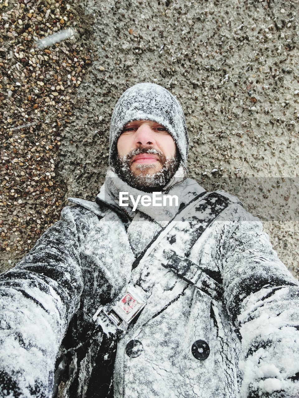 Portrait of mature man covered with snow standing against wall
